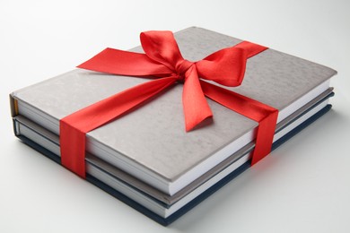 Photo of Books tied with red ribbon on white background, closeup