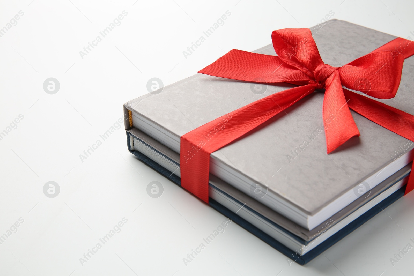 Photo of Books tied with red ribbon on white background, closeup. Space for text