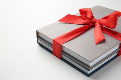 Photo of Books tied with red ribbon on white background, closeup. Space for text