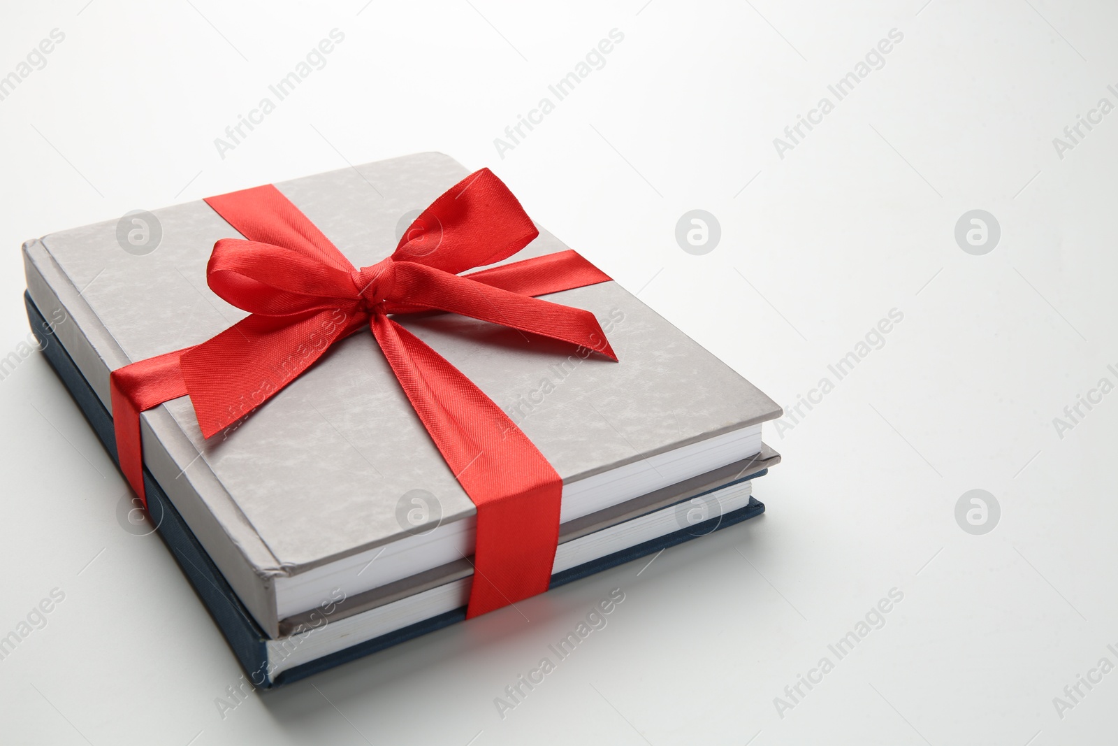 Photo of Books tied with red ribbon on white background. Space for text