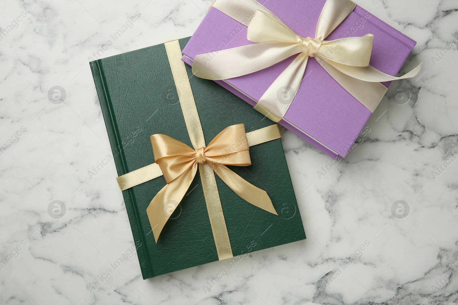 Photo of Books tied with ribbons on white marble table, top view