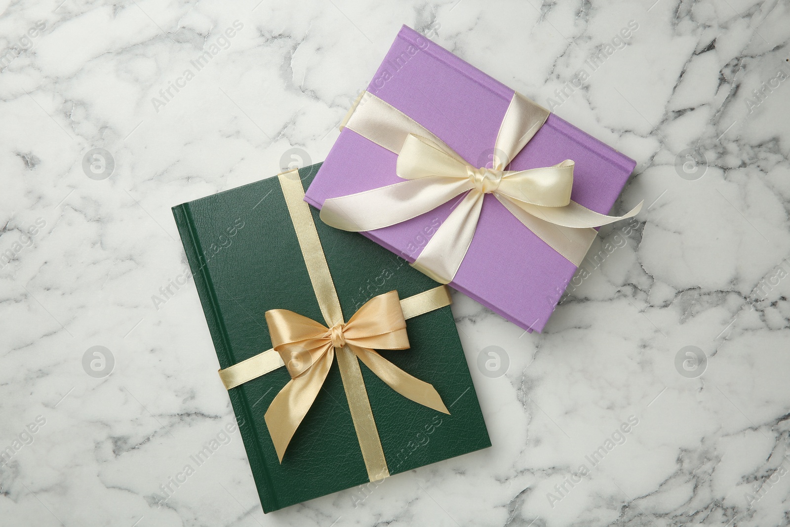 Photo of Books tied with ribbons on white marble table, top view