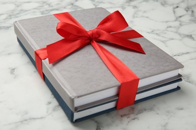 Photo of Books tied with red ribbon on white marble table, closeup