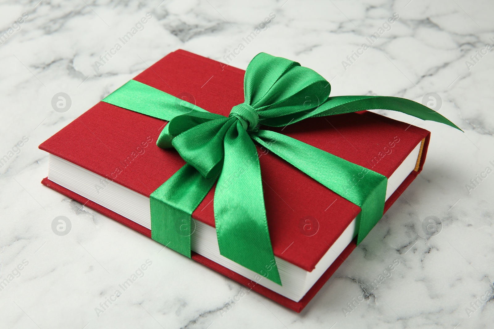 Photo of Book tied with green ribbon on white marble table