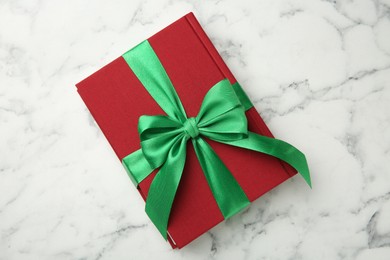 Photo of Book tied with green ribbon on white marble table, top view