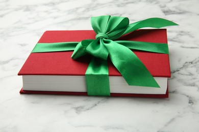 Photo of Book tied with green ribbon on white marble table, closeup