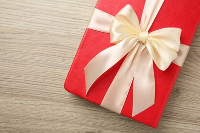 Book tied with beige ribbon on wooden table, top view. Space for text