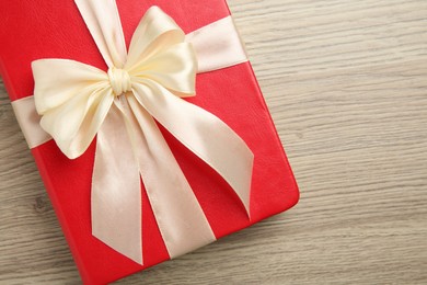 Book tied with beige ribbon on wooden table, top view. Space for text