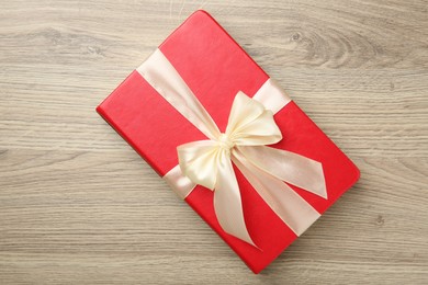 Photo of Book tied with beige ribbon on wooden table, top view