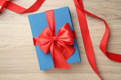 Photo of Book tied with red ribbon on wooden table, top view