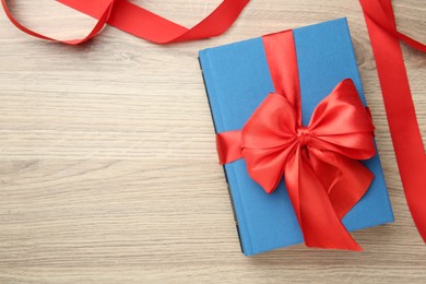 Photo of Book tied with red ribbon on wooden table, top view. Space for text