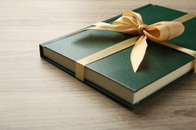 Photo of Book tied with golden ribbon on wooden table, closeup