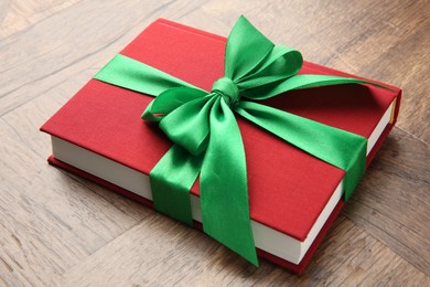 Book tied with green ribbon on wooden table, closeup