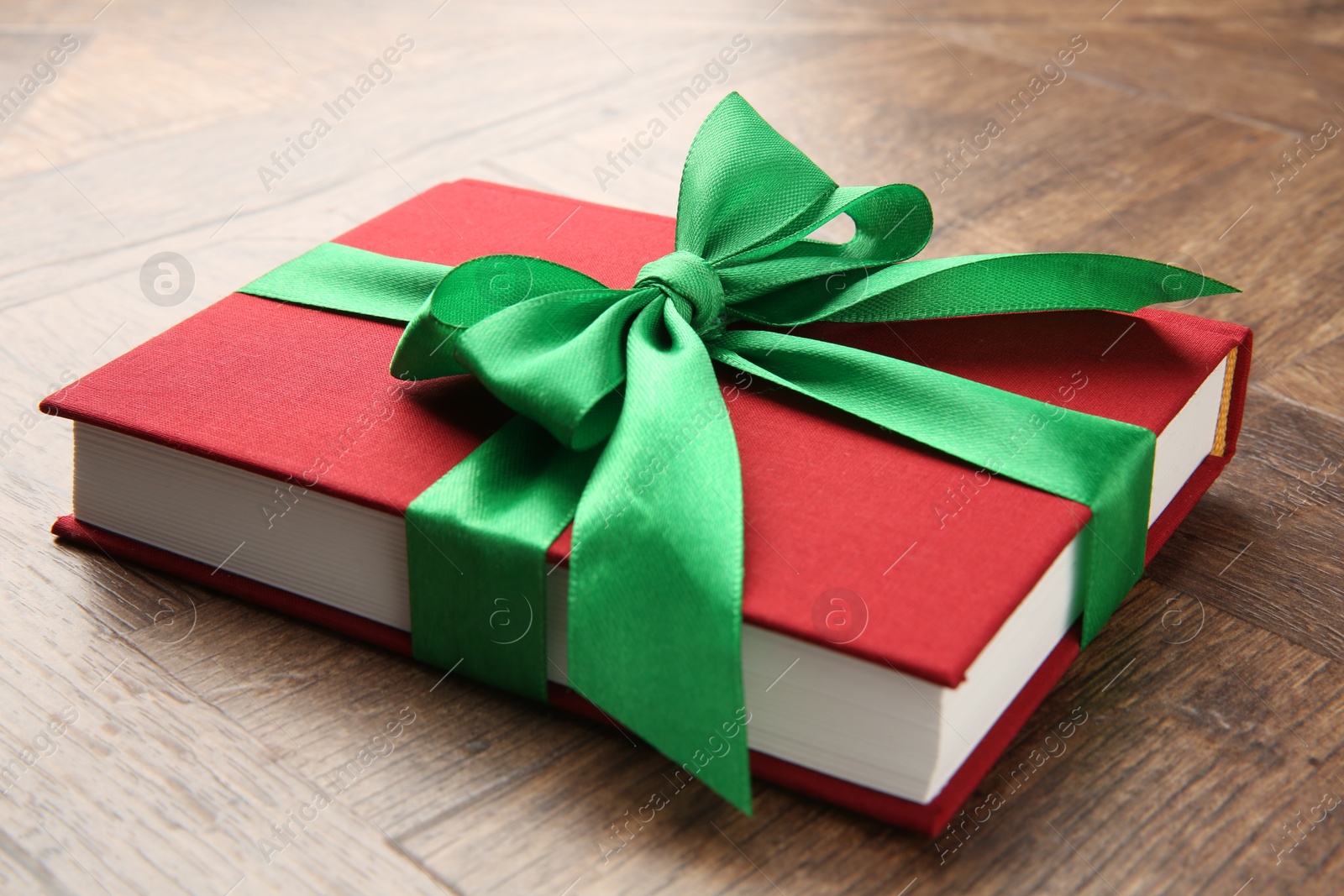 Photo of Book tied with green ribbon on wooden table, closeup