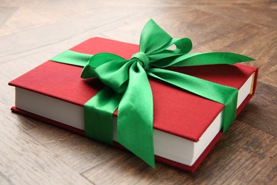 Book tied with green ribbon on wooden table, closeup