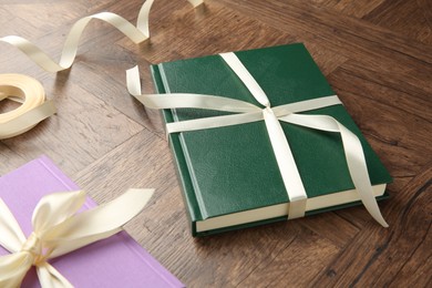 Photo of Hardcover books and ribbon as gift on wooden table