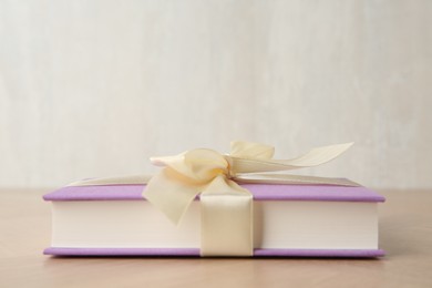 Hardcover book with ribbon as gift on wooden table