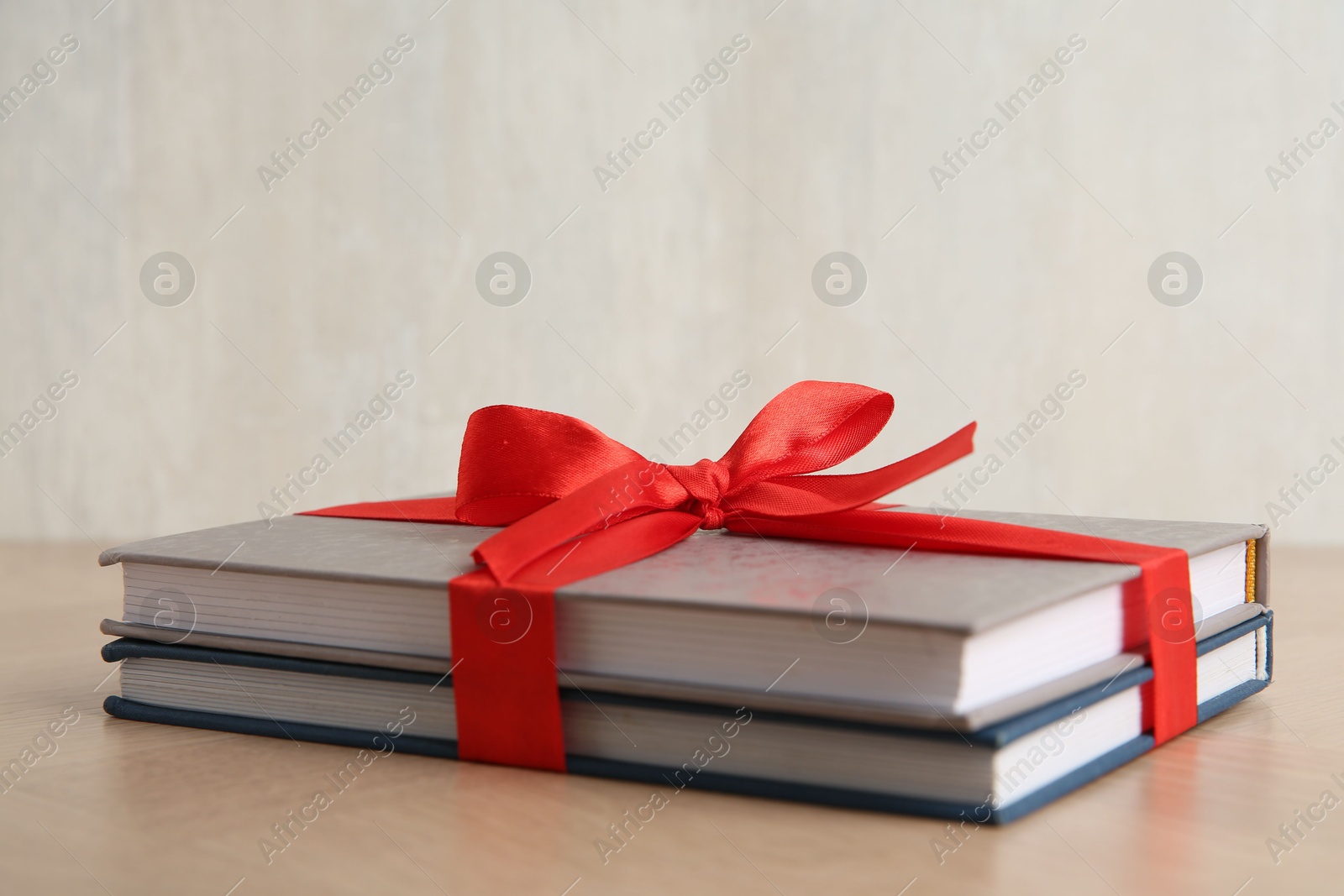 Photo of Hardcover books with ribbon as gift on wooden table