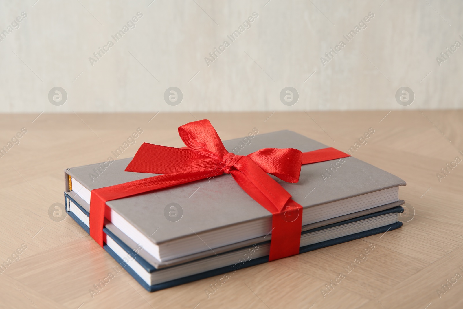 Photo of Hardcover books with ribbon as gift on wooden table