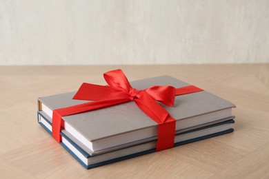 Photo of Hardcover books with ribbon as gift on wooden table