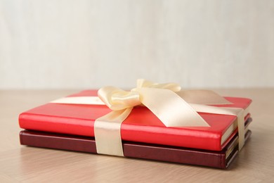 Photo of Hardcover books with ribbon as gift on wooden table