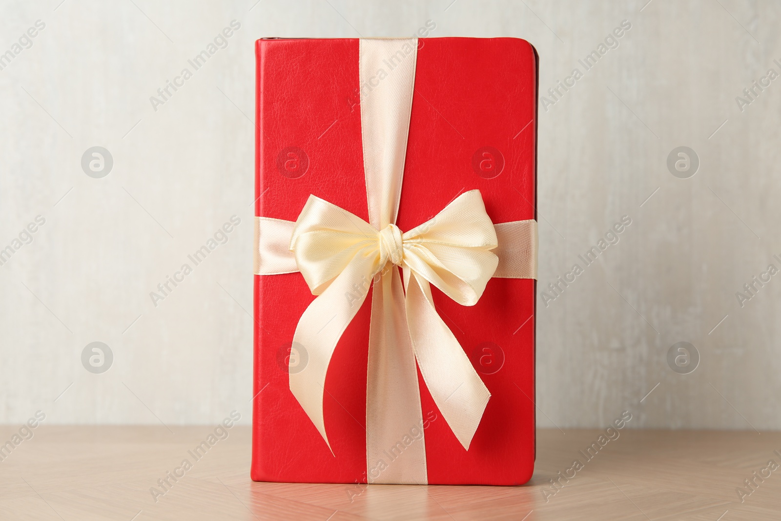 Photo of Hardcover book with ribbon as gift on wooden table