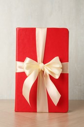 Photo of Hardcover book with ribbon as gift on wooden table