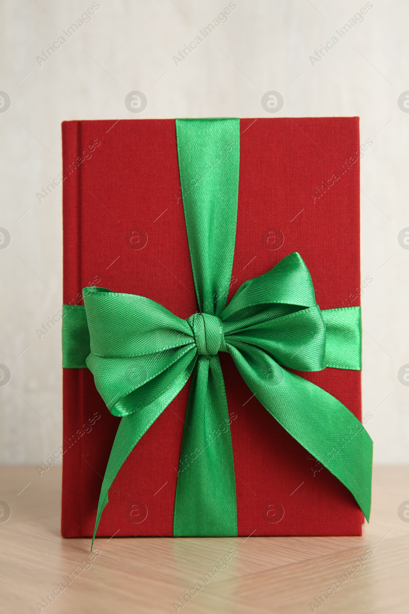 Photo of Hardcover book with ribbon as gift on wooden table