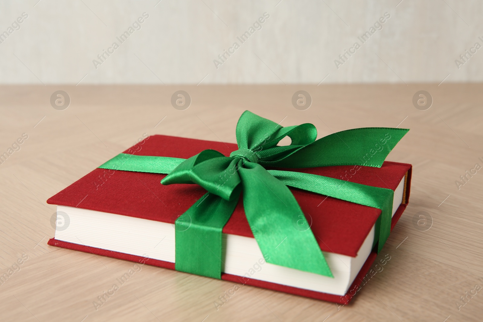 Photo of Hardcover book with ribbon as gift on wooden table