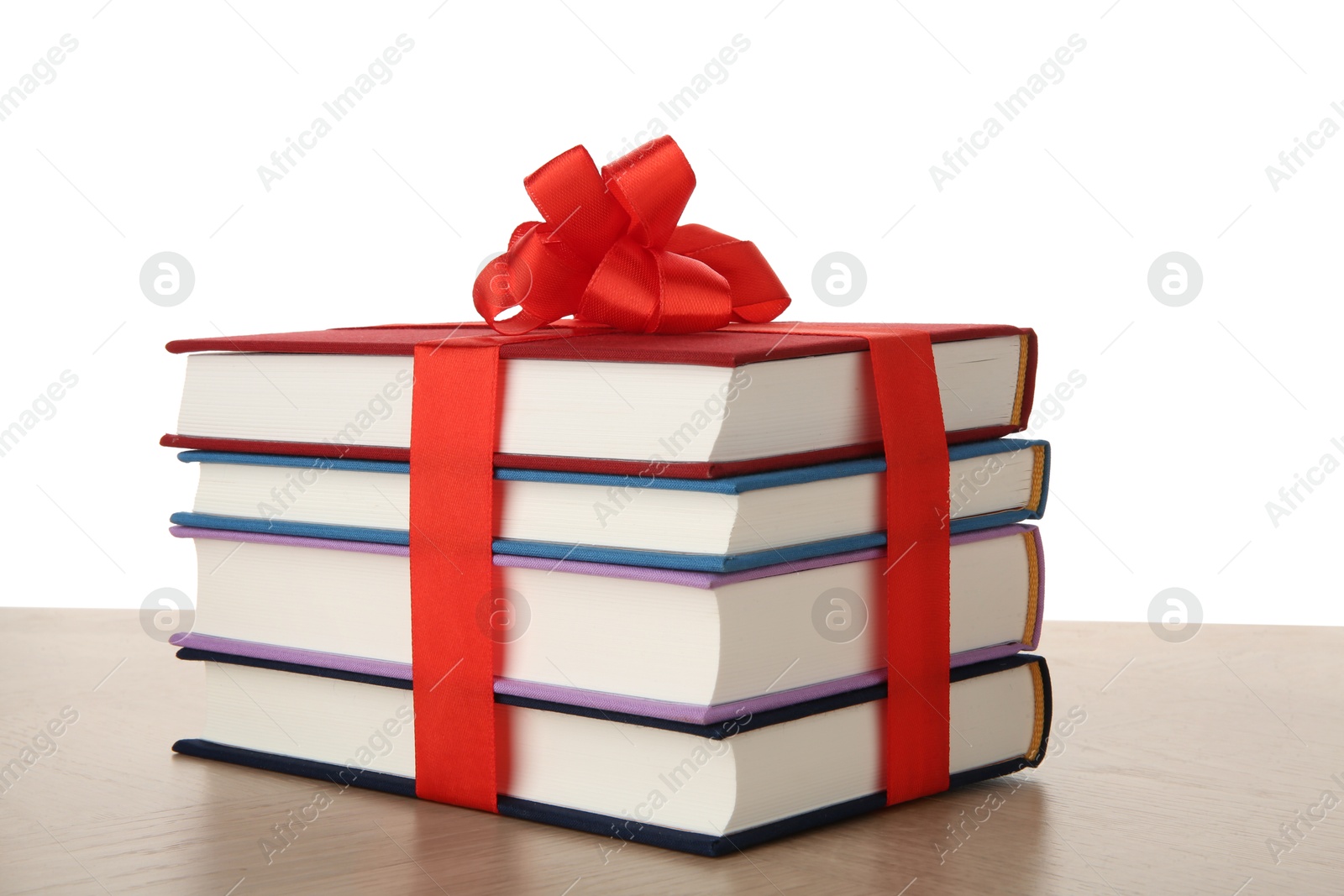 Photo of Stack of books with ribbon as gift on wooden table against white background