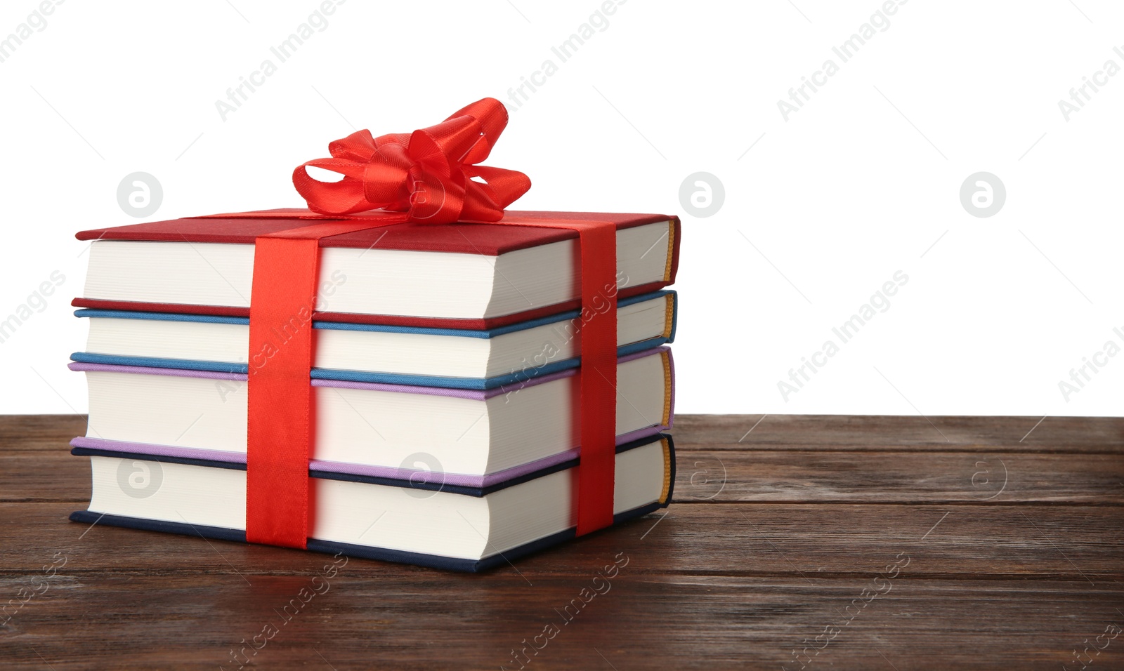 Photo of Stack of books with ribbon as gift on wooden table against white background