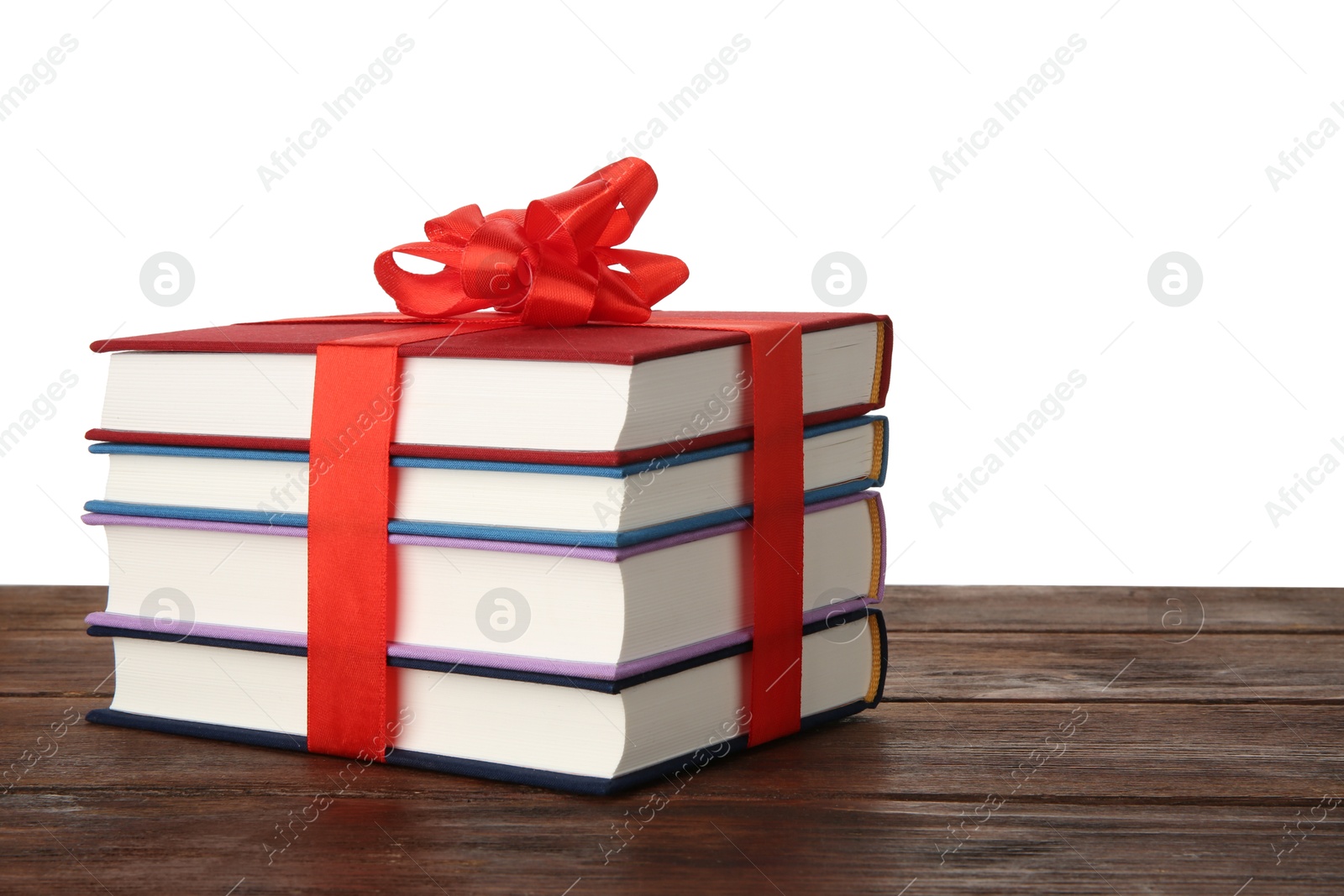 Photo of Stack of books with ribbon as gift on wooden table against white background