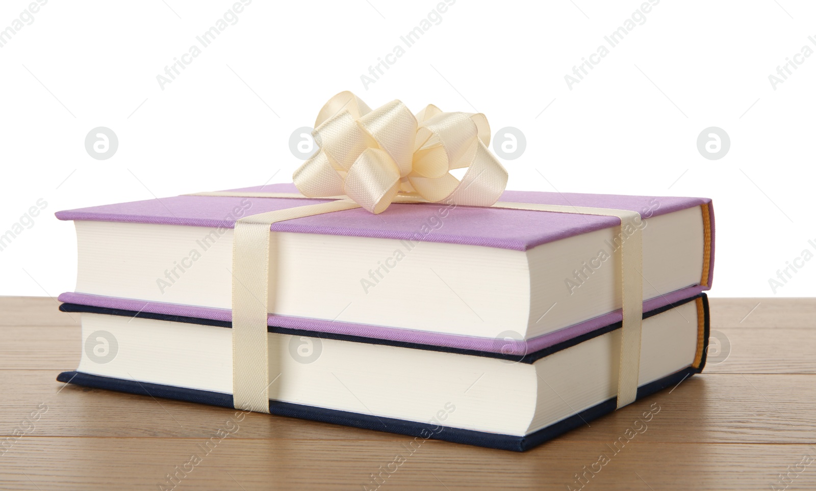 Photo of Hardcover books with ribbon as gift on wooden table against white background