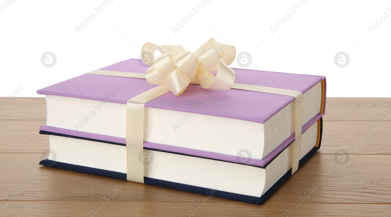 Photo of Hardcover books with ribbon as gift on wooden table against white background