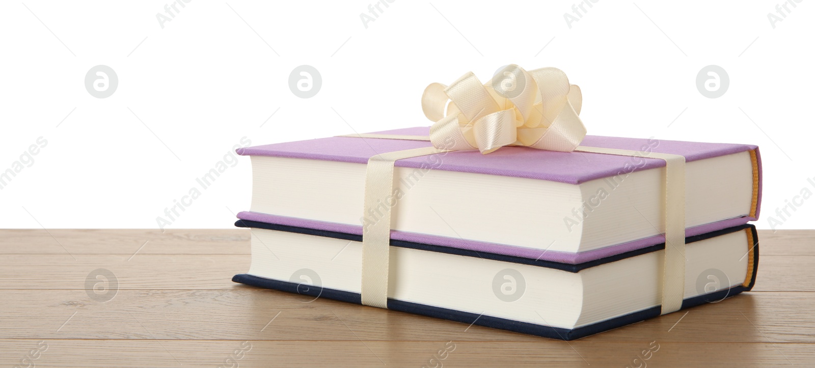 Photo of Hardcover books with ribbon as gift on wooden table against white background