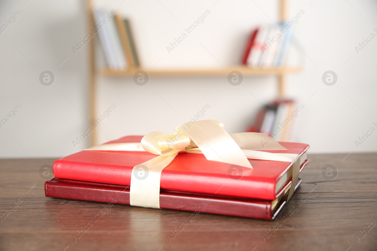 Photo of Hardcover books with ribbon as gift on wooden table indoors