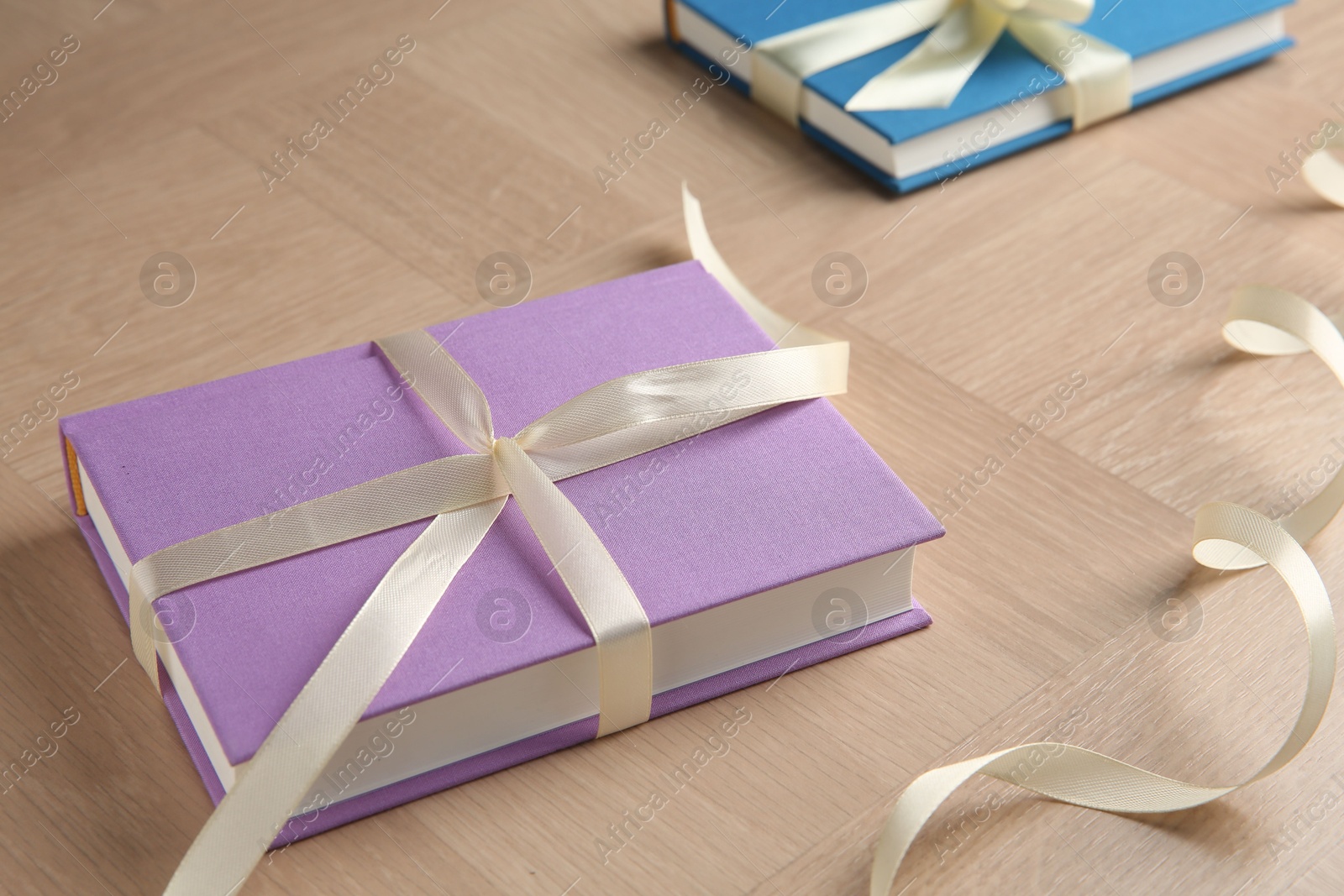 Photo of Hardcover books with ribbons as gift on wooden table