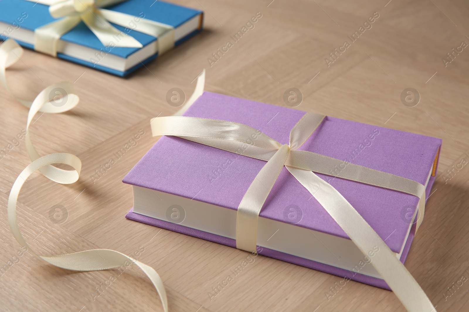 Photo of Hardcover books with ribbons as gift on wooden table