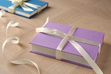 Photo of Hardcover books with ribbons as gift on wooden table