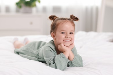 Portrait of happy little girl on bed at home