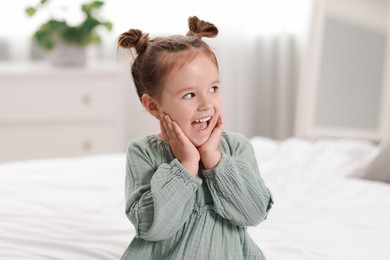 Portrait of emotional little girl in bedroom