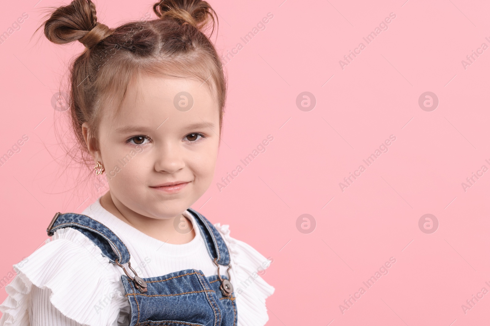 Photo of Portrait of cute little girl on pink background, space for text