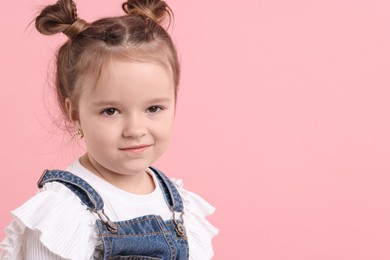 Photo of Portrait of cute little girl on pink background, space for text