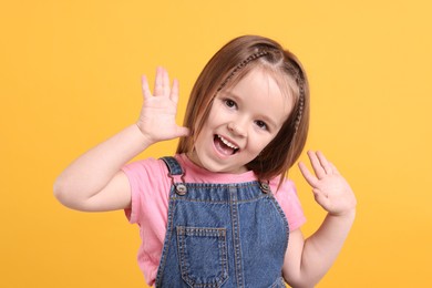 Portrait of emotional little girl on orange background