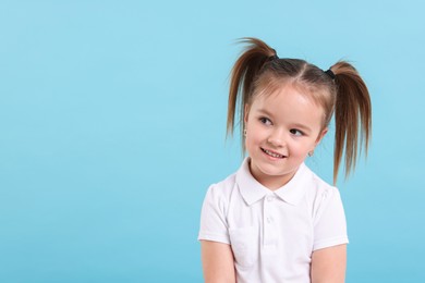 Photo of Portrait of happy little girl on light blue background, space for text