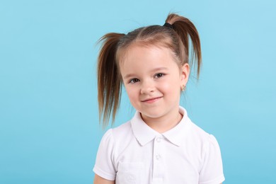 Portrait of cute little girl on light blue background