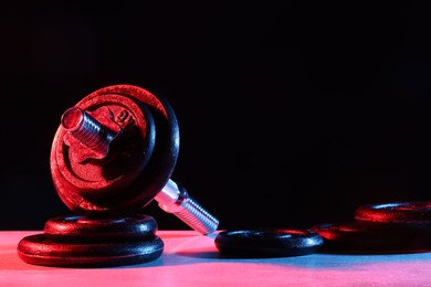 Photo of Parts of barbell on table in color lights. Space for text