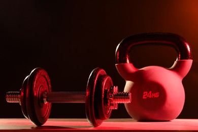 Barbell and kettlebell on table in color lights