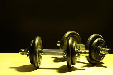 Photo of Two barbells on table in color lights. Space for text