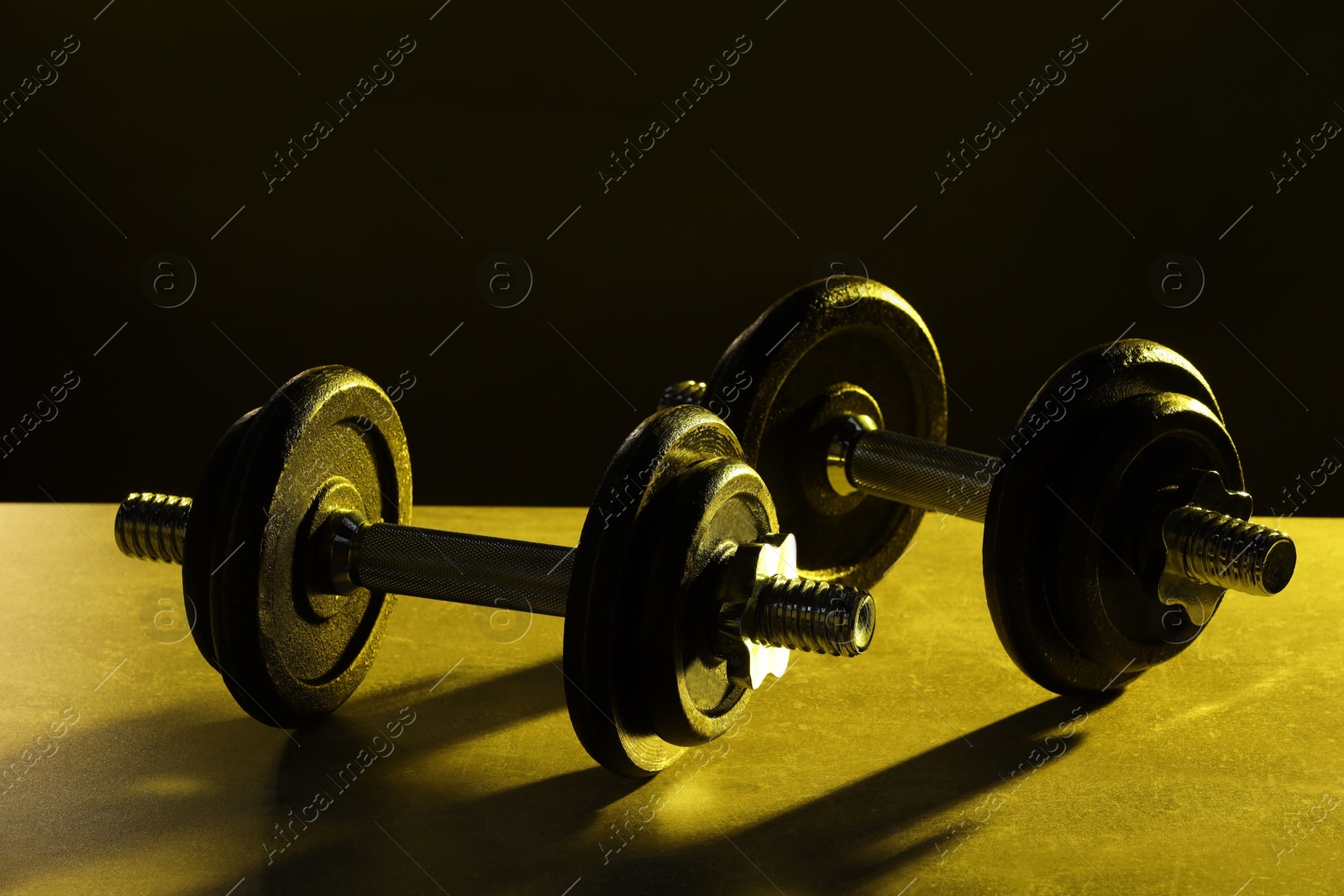 Photo of Two barbells on table in color lights